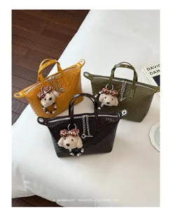 Woven dumpling handbag detail showcasing textured leather, zipper closure and cute dog charm.