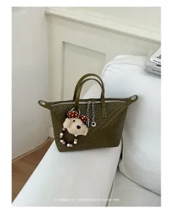 Close-up detail of the elegant olive green woven dumpling bag with cute puppy charm.