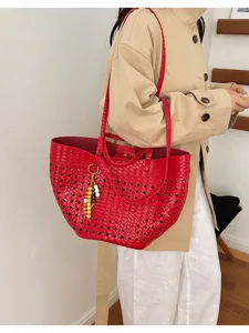 Detail shot of the red woven leather tote bag showing hollow pattern and charm accessory.