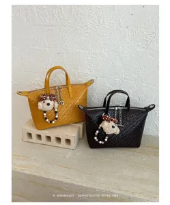 Detailed view of fashionable woven dumpling handbag with cute plush puppy keychain charm.
