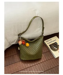 Detailed view of the retro green woven bucket bag with stylish charm and smooth shoulder strap.