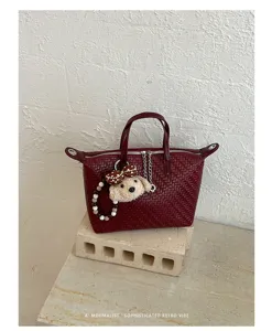 Close-up detail of the dark red woven tote bag featuring a cute puppy plush charm pendant.