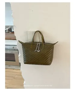 Olive green woven leather handbag detail shot featuring stylish chain and minimalist retro design.