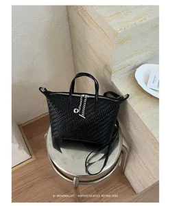 Detail view of black woven dumpling handbag with metal hardware, chic commuting crossbody bag.