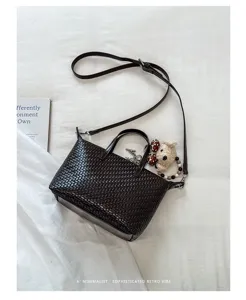 Elegant dark brown woven leather crossbody dumpling bag with cute bear pendant for women.