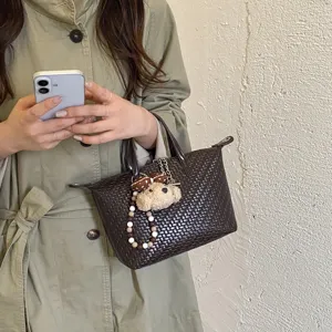 Woven dumpling handbag for women autumn fashion commuter crossbody bag with plush bear charm.