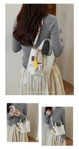 Detailed view of white leather bucket bag with cute horse charm and gold lock for women.