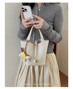 Minimalist leather bucket handbag detail, elegant white design with chic charm and lock.