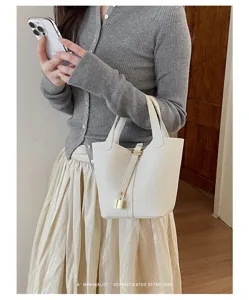 Elegant white leather bucket bag for women, featuring a chic lock design and comfortable handles.