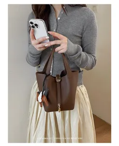 Detail view of a stylish brown leather bucket handbag with charm, perfect for daily wear.