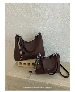 Detailed view of women retro brown shoulder bag with chic hanging charm and texture.