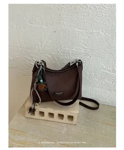 Minimalist retro brown shoulder bag detail showing textured fabric and stylish hanging charm.