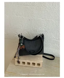 Detailed view of the minimalist retro shoulder bag with textured fabric and chic pendant.