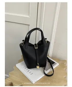 Black leather bucket bag with top handle and padlock, minimalist stylish handbag for women.