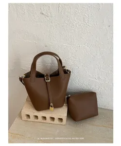 Detailed shot of a minimalist brown leather bucket bag with matching pouch and chic lock detail.