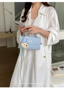 Light blue quilted handbag detail showing chain handle, turn-lock and cute bear charm.