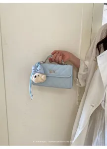 Light blue quilted mini handbag with chain handle and cute puppy charm, chic retro style.