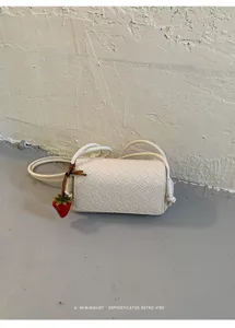 White woven leather crossbody bag with chic strap and cute strawberry charm for women.