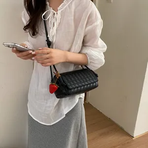 Black woven leather crossbody bag with cute strawberry charm, stylish underarm shoulder bag.