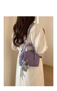 Vue détaillée d'un sac Boston violet chic porté à l'épaule, avec charmant pendentif élégant.