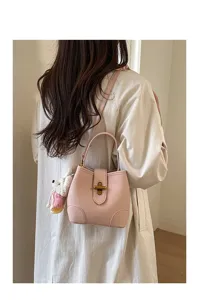 Dettaglio borsa secchiello in pelle rosa con elegante chiusura metallica e ciondolo.