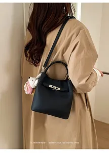 Detailed view of a black litchi pattern leather bucket bag with top handle and metal lock.