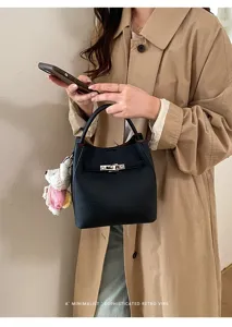 Black leather bucket bag detail featuring chic turn-lock hardware and cute knitted charm.