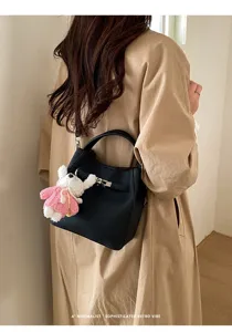 Black minimalist textured bucket bag with top handle and cute rabbit charm for women.
