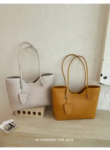 Vista dettagliata della borsa tote con trama intrecciata in colori neutri e gialli autunnali.