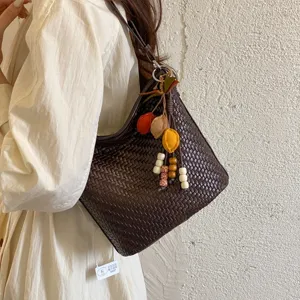 Retro woven hobo shoulder bag for women, stylish casual bucket bag with cute charm pendant.