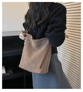 Vista dettagliata della borsa a secchiello intrecciata da donna con finiture in pelle marrone.