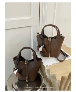 Brown leather bucket bag with top handles, chic metal lock closure and winged horse charm.