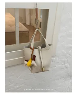 Detailed close-up view of cream leather bucket bag featuring padlock and cute horse charm.