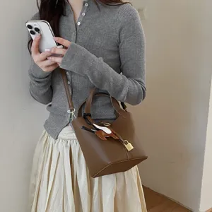 Stylish brown leather bucket bag for women, chic shoulder crossbody handbag with lock charm.
