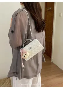 White quilted shoulder bag with chain strap, metal handle and cute bear pendant for women.