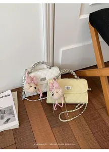 Close-up detail of chic quilted shoulder bag with cute bear charm and chain strap aesthetic.