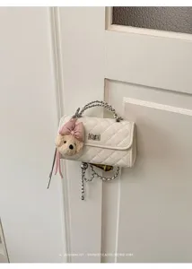 Detailed view of white quilted mini handbag with chain strap and cute bear charm pendant.