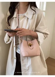 Primo piano di una elegante borsa a secchiello in pelle rosa con chiusura in metallo.
