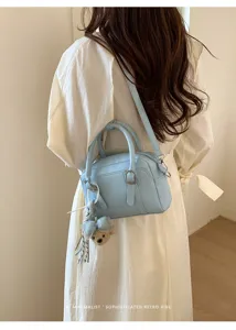 Vue détaillée d'un sac à main Boston bleu clair avec un charm ourson au dos.