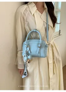 Vue détaillée du sac Boston bleu clair porté par le mannequin, affichant une texture en cuir élégante.