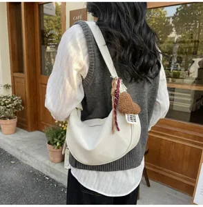 Detailed view of a trendy white crescent shoulder bag with cute heart charm and stylish strap.