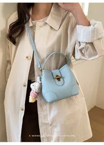 Dettaglio ravvicinato della borsa a secchiello in pelle azzurra con ciondolo coniglietto.