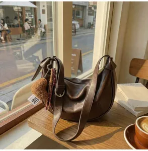 Detailed close-up view of the vintage brown slouchy hobo shoulder bag set in a cozy cafe scene.