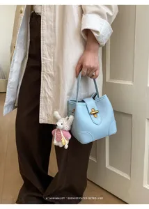 Elegante borsa a secchiello in pelle azzurra con chiusura metallica e ciondolo chic.