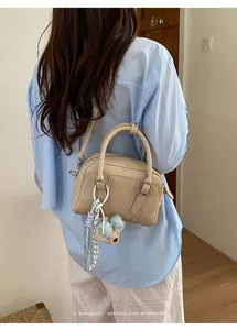 Vue détaillée d'un élégant sac à main Boston beige rétro minimaliste porté à l'épaule chic.