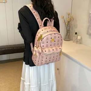 Vista dettagliata di uno zaino rosa con stampa monogramma e dettagli metallici dorati.