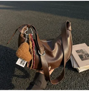 Retro brown hobo shoulder bag detail featuring plush heart charm, wide strap and casual design.
