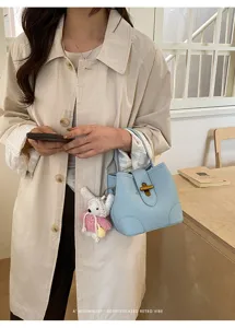 Vista dettagliata dell'elegante borsa a secchiello azzurro con ciondolo coniglio e serratura.