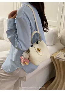 Dettaglio borsa a secchiello bianca con chiusura a girello e grazioso ciondolo orsetto.