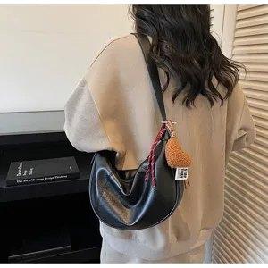 Detailed view of black leather hobo bag with cute plush charm and casual daily style.